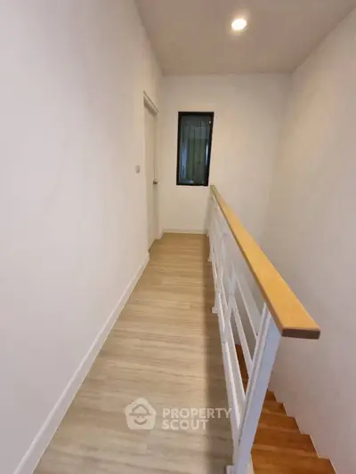 Modern hallway with wooden flooring and sleek railing in a contemporary home.