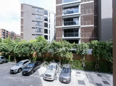 Modern apartment building with spacious parking area and lush greenery