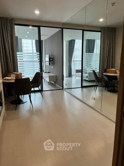 Modern living room with mirrored wall and elegant dining area in a stylish apartment.