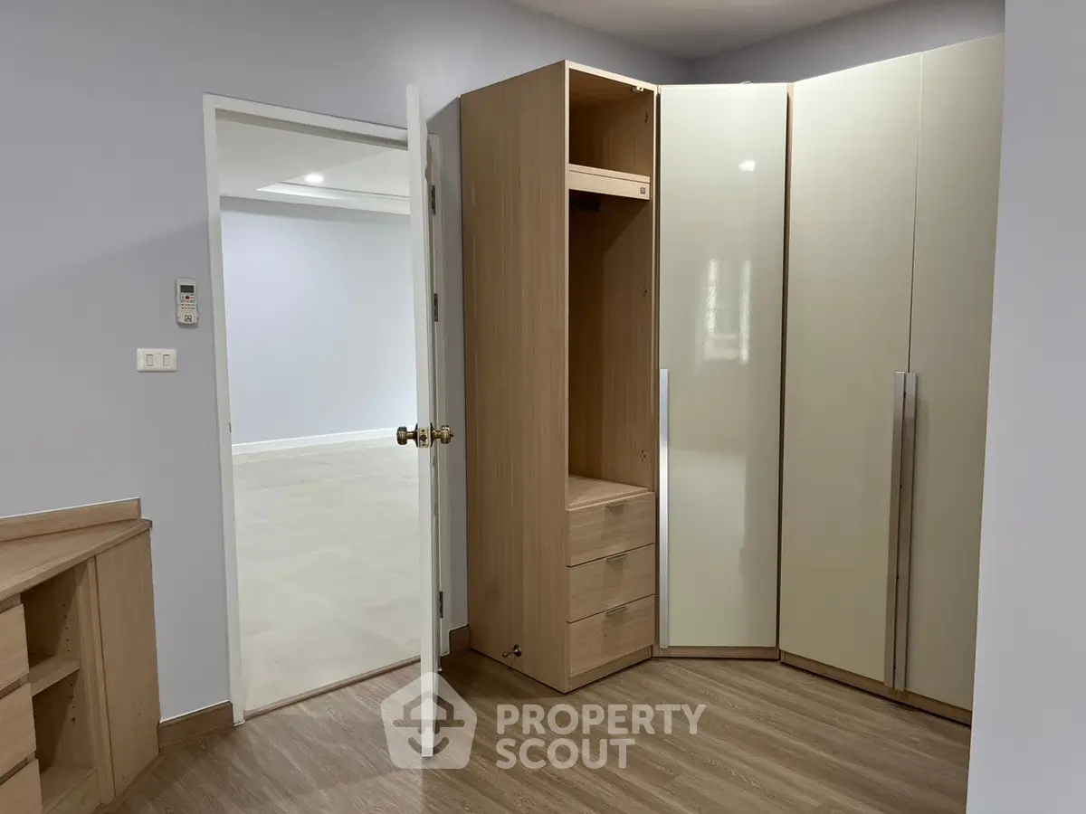 Spacious bedroom with modern built-in wardrobe and wooden flooring