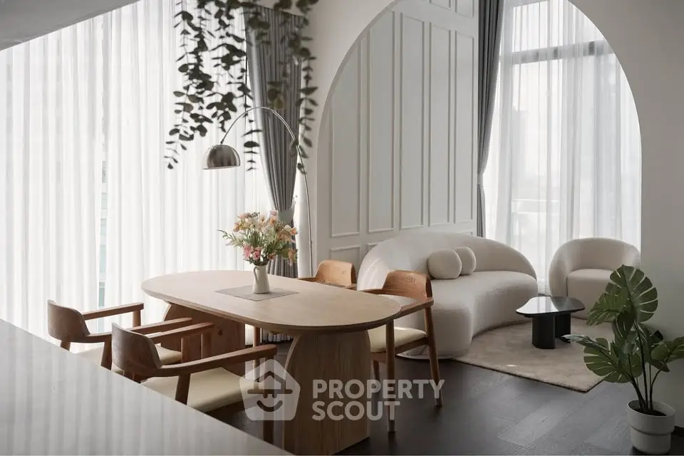 Elegant modern living room with stylish furniture and large windows, featuring a cozy dining area and chic decor.