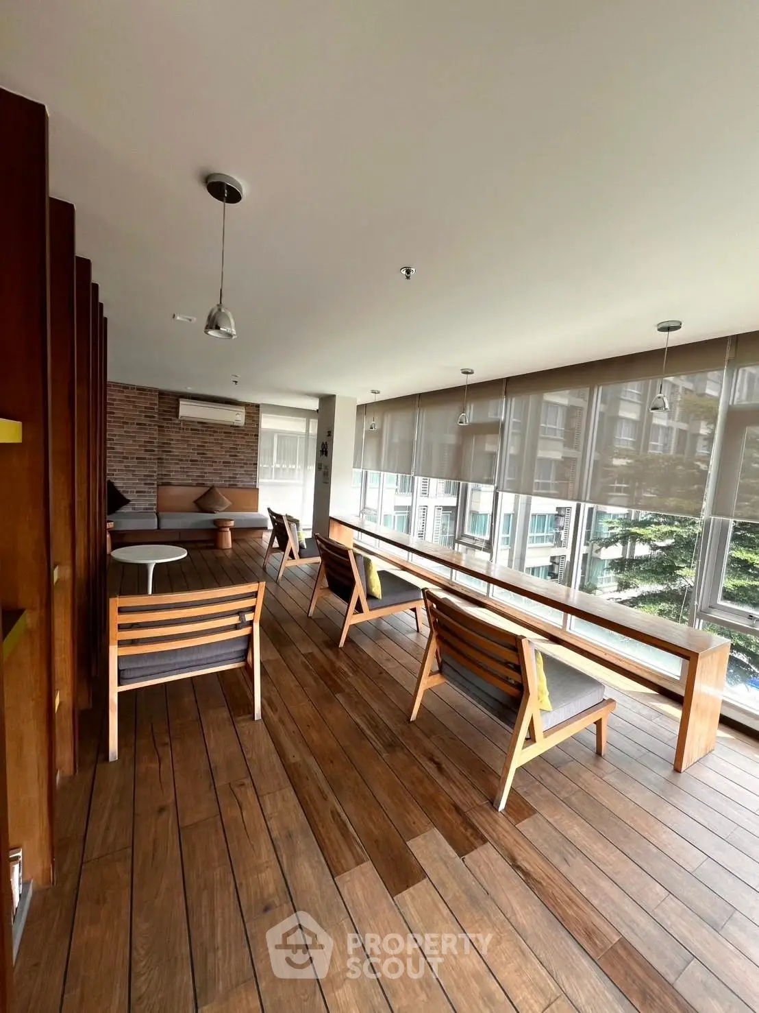 Stylish modern lounge area with wooden flooring and large windows offering natural light and outdoor views.