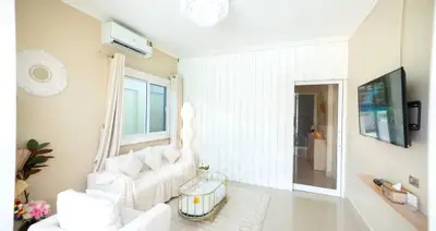 Elegant living room with modern decor, featuring a cozy white sofa, wall-mounted TV, and stylish lighting.