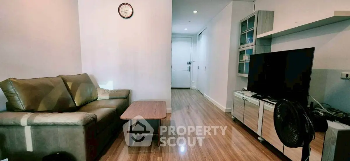 Modern living room with sleek wooden flooring, cozy sofa, and entertainment center, perfect for relaxation.