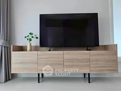 Modern living room with sleek wooden TV stand and large flat-screen TV, complemented by elegant curtains.