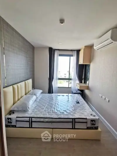 Modern bedroom with stylish decor and natural light, featuring a comfortable bed and air conditioning.