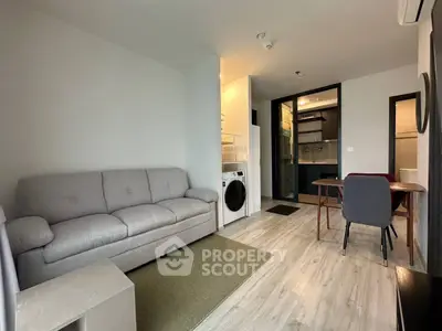 Modern living room with cozy sofa, dining area, and in-unit washer in a stylish apartment.