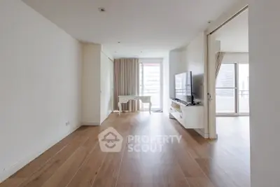 Spacious modern living room with wooden flooring and large windows in a high-rise apartment.