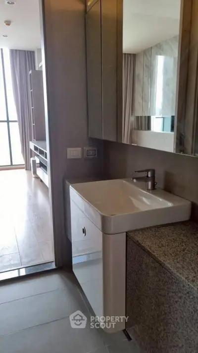 Modern bathroom with sleek sink and large mirror in a stylish apartment.
