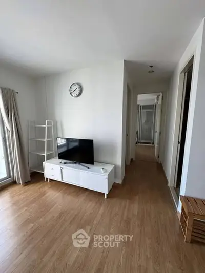 Modern living room with wooden flooring and TV unit in a bright apartment