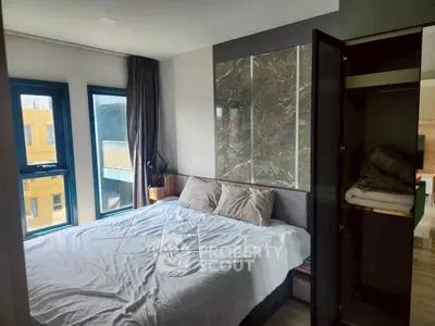 Modern bedroom with large windows and stylish decor in a contemporary apartment.