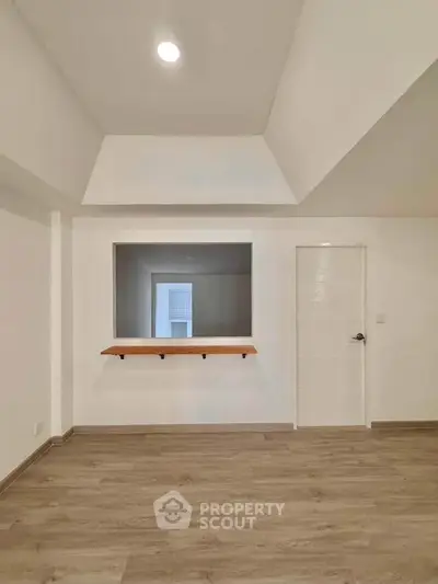 Spacious modern interior with wooden flooring and pass-through window, ideal for open living.