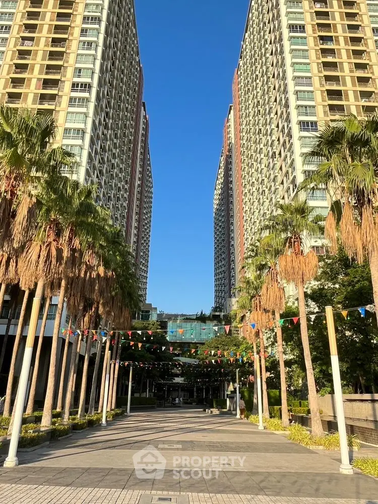 Stunning high-rise apartment buildings with palm-lined entrance and festive flags.