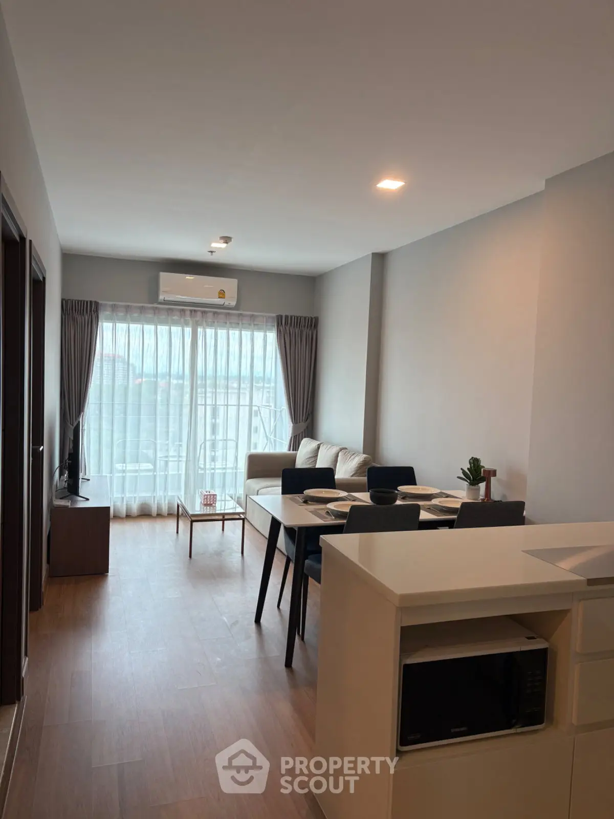 Modern living room with dining area and large windows in a stylish apartment.