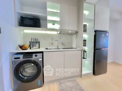 Modern kitchen with sleek appliances and integrated washing machine in stylish apartment.