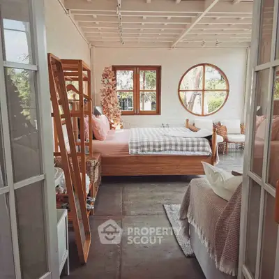 Charming rustic bedroom with large round window and cozy decor.