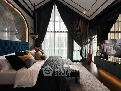 Luxurious bedroom with high ceilings, elegant decor, and large windows offering natural light.