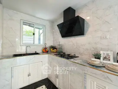 Modern kitchen with marble countertops and sleek black range hood