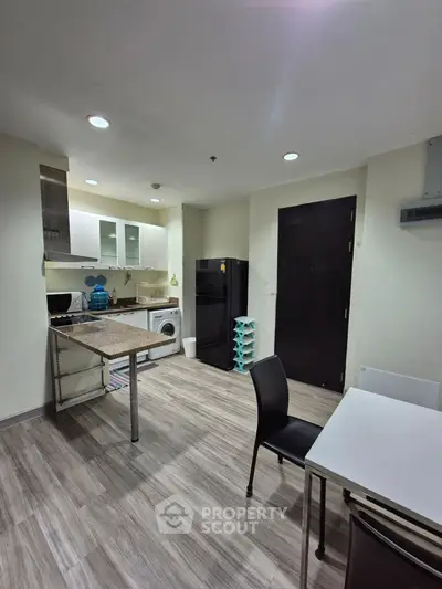 Modern kitchen with sleek appliances and open layout, featuring a washing machine and dining area.