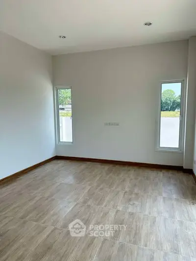 Spacious empty room with large windows and wooden flooring, perfect for customization.