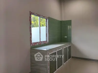 Modern kitchen with green tiled backsplash and large window