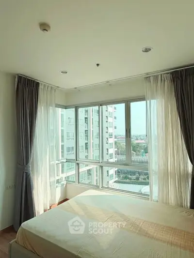 Bright bedroom with large windows offering a stunning city view in a modern apartment.