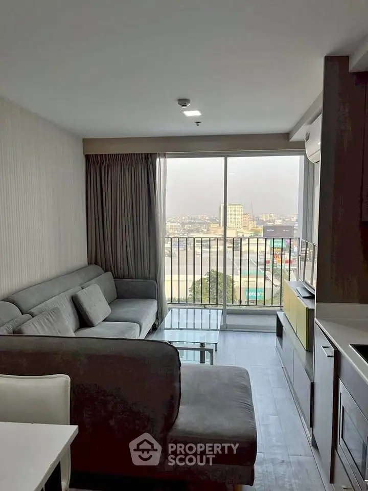 Modern living room with city view, featuring sleek gray sofa and large window for natural light.