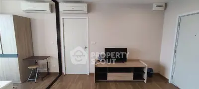 Modern living room with air conditioning and wooden flooring, featuring a TV stand and compact workspace.