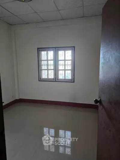 Spacious empty room with window and tiled floor, perfect for customization.