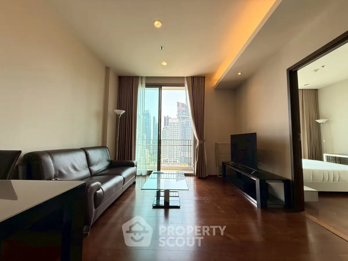 Modern living room with city view, featuring sleek furniture and large windows for natural light.