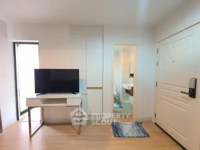 Modern apartment interior with TV and bathroom view, featuring sleek design and wooden flooring.