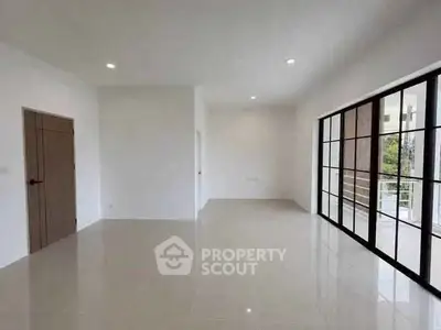Spacious modern living room with large windows and sleek tile flooring.