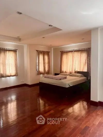 Spacious bedroom with wooden flooring and natural light