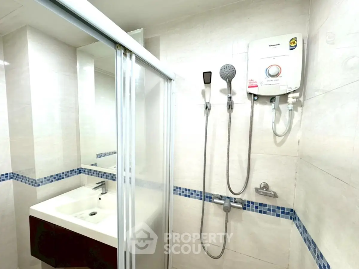 Modern bathroom with shower and sink featuring sleek design and bright lighting.