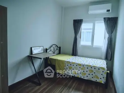 Cozy bedroom with single bed, desk, and air conditioning in modern apartment.
