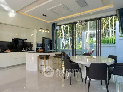 Luxurious modern kitchen with open layout and elegant dining area, featuring sleek cabinetry and large windows.