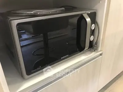 Modern kitchen with sleek Samsung microwave in built-in cabinet.