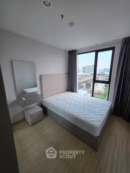 Modern bedroom with large window and city view, featuring a comfortable bed and minimalist decor.