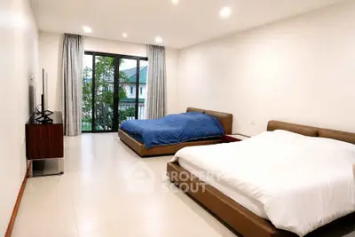 Spacious bedroom with two beds and large window offering natural light and garden view.