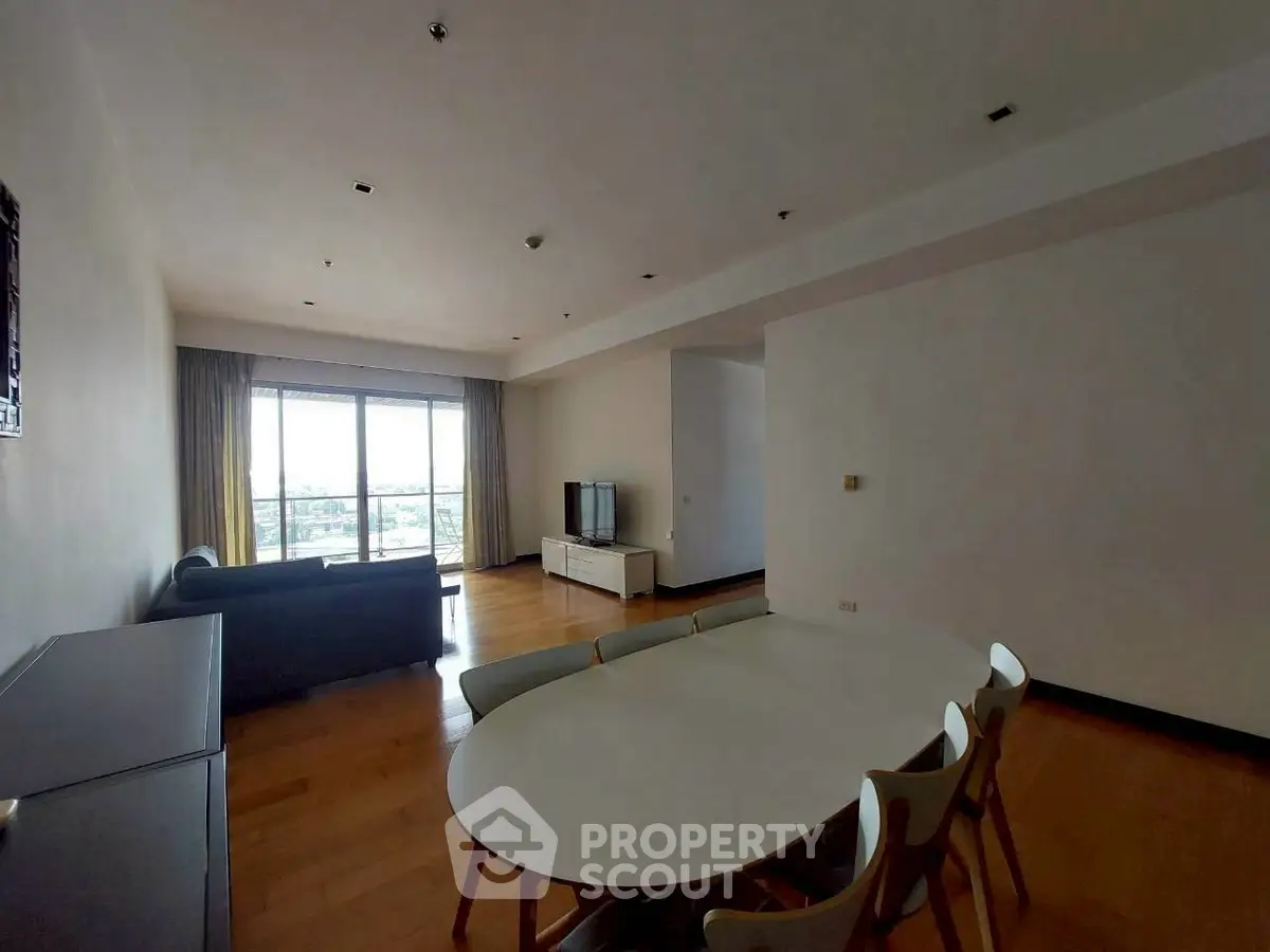 Spacious living room with modern furniture and large window offering city views.