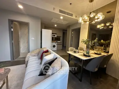 Modern living room with elegant dining area and stylish lighting, featuring a cozy sofa and contemporary decor.