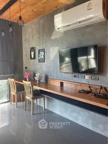 Modern living room with sleek design, featuring a wall-mounted TV and stylish workspace.