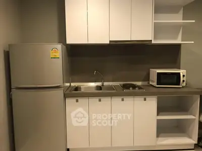 Modern compact kitchen with fridge, microwave, and sleek cabinetry