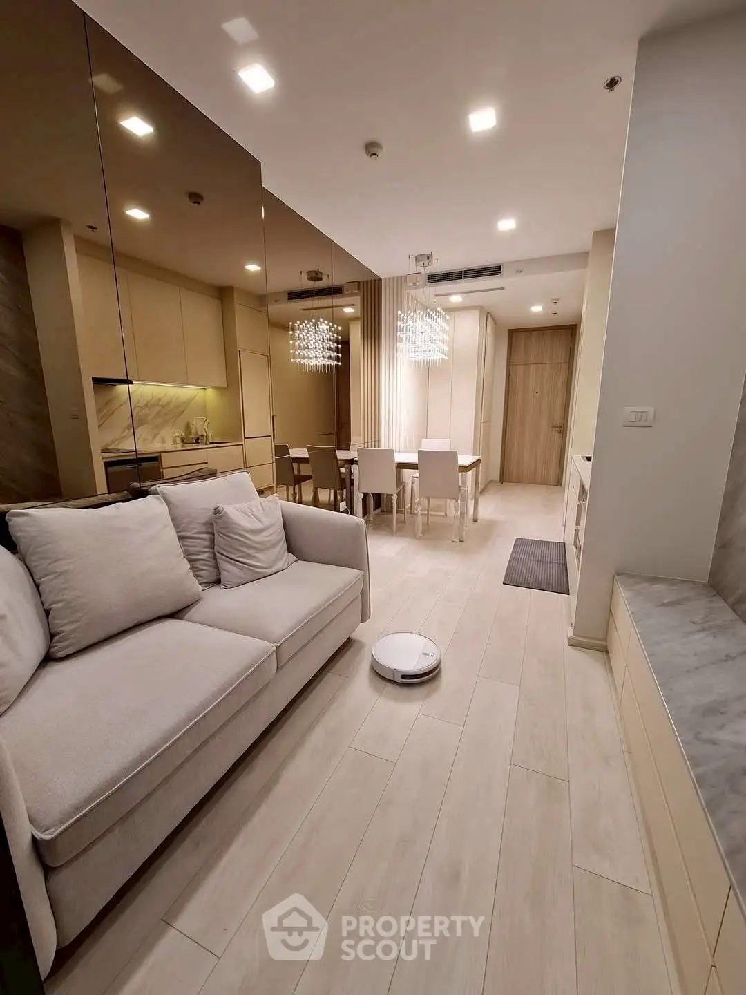 Modern open-plan living room with sleek kitchen and dining area, featuring elegant lighting and neutral tones.