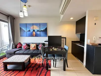 Modern living room with stylish decor and open kitchen layout, featuring a cozy sofa and vibrant rug.