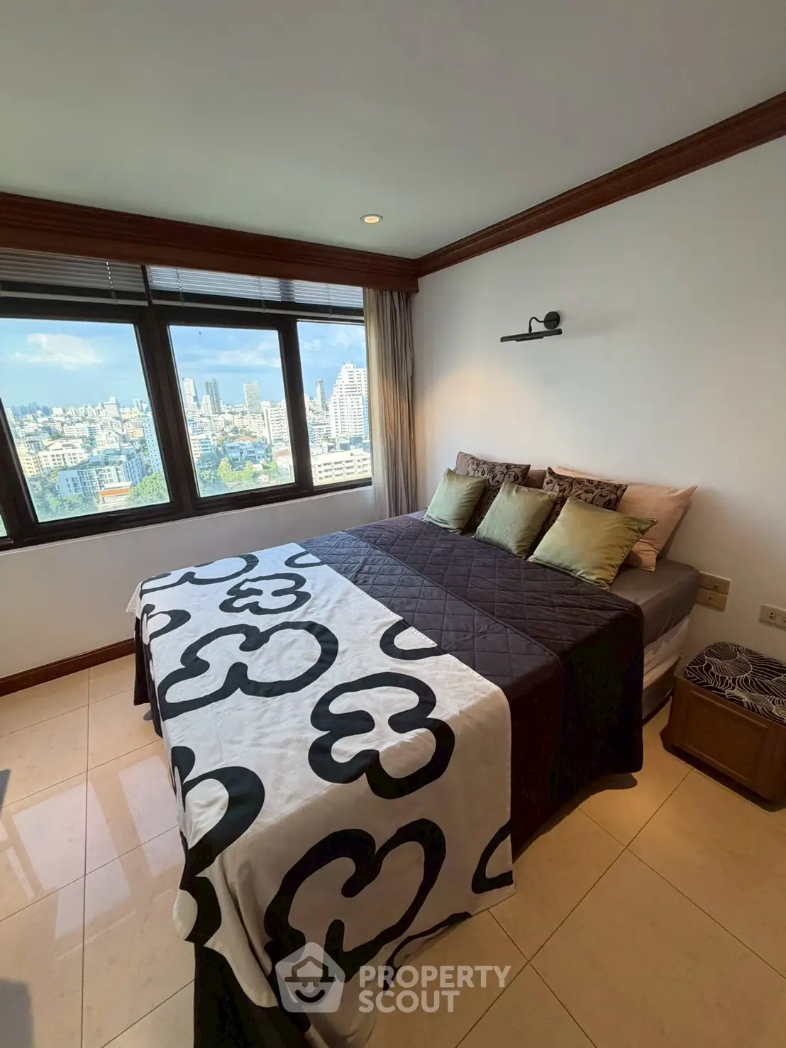 Spacious bedroom with city view, large windows, and modern decor in high-rise apartment.