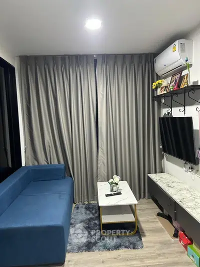 Modern living room with blue sofa, marble table, and wall-mounted TV in cozy apartment.