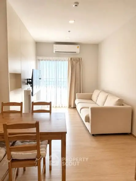 Modern living room with natural light, cozy sofa, and dining area in a stylish apartment.
