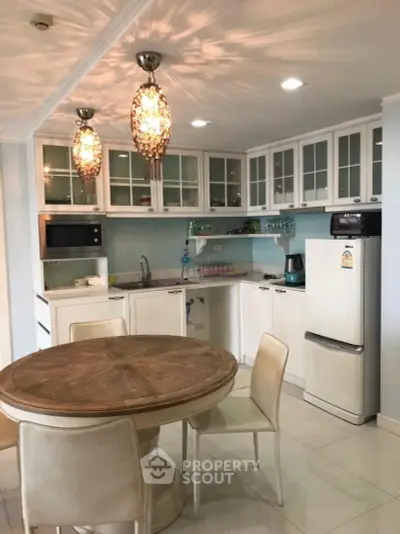 Charming kitchen with elegant lighting, modern appliances, and cozy dining area in a stylish home.
