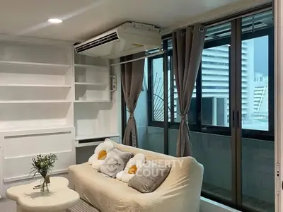 Modern living room with cozy sofa and large windows leading to a balcony with city view.